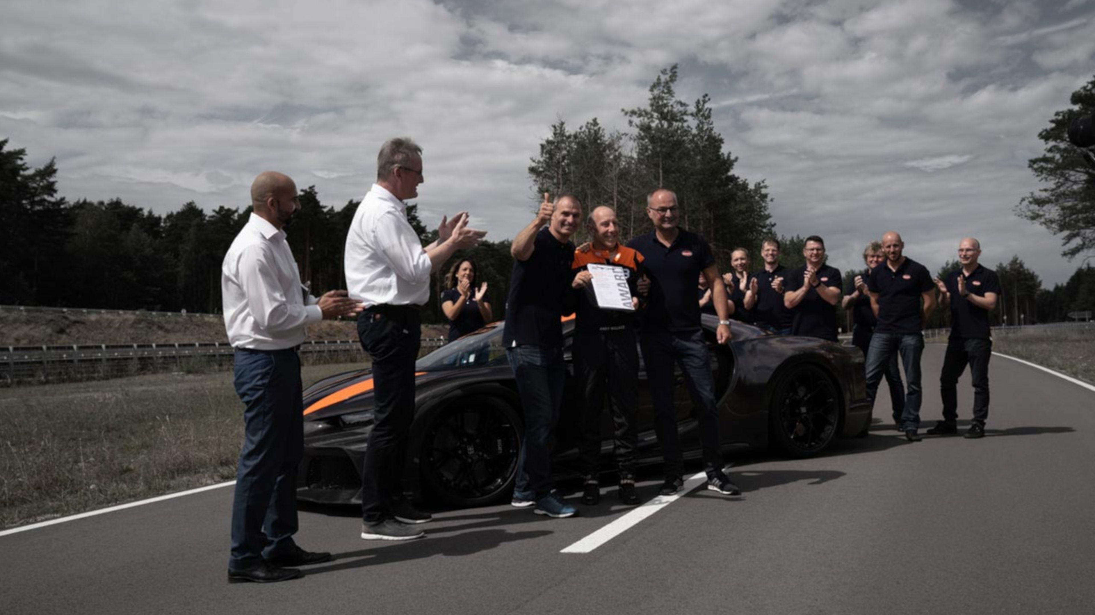 En el centro de la imagen, Andy Wallace posa orgulloso con el certificado TÜV que acredita el récord de velocidad logrado.